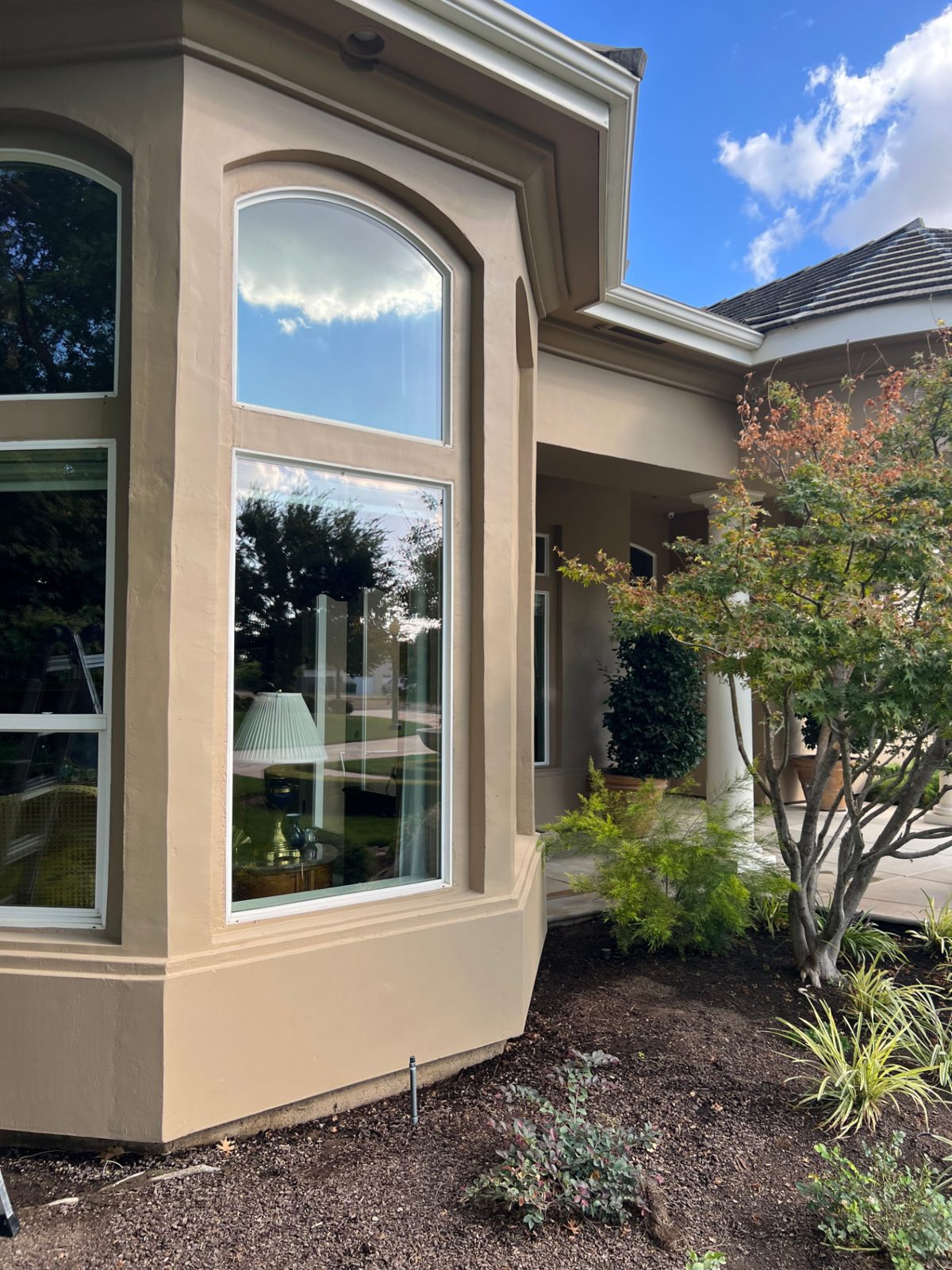 Large bay window on a Fresno home reflecting clear blue sky after cleaning